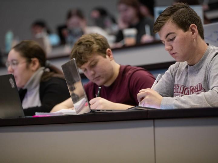 A student listens and takes notes while in a lecture room