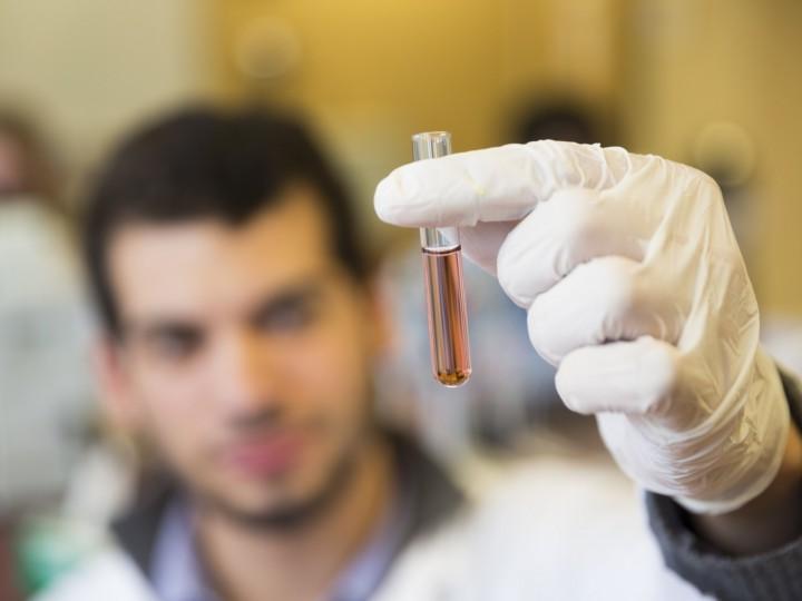 Close up of student holding a test tube filled with red liquid